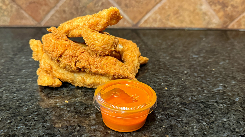 Clear container of Zaxby's Buffalo Garlic Blaze Sauce and chicken tenders